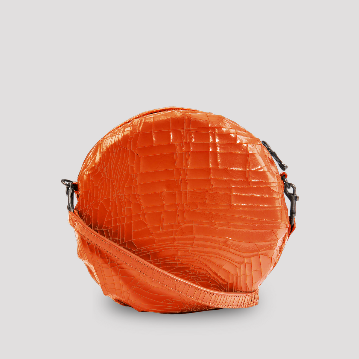 Close-up of a bright orange baby macaron by Marc Marmel, showcasing its smooth, delicate shell and creamy filling.
